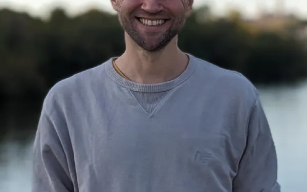 an image of Marcel in front of a body of water with forest in the background